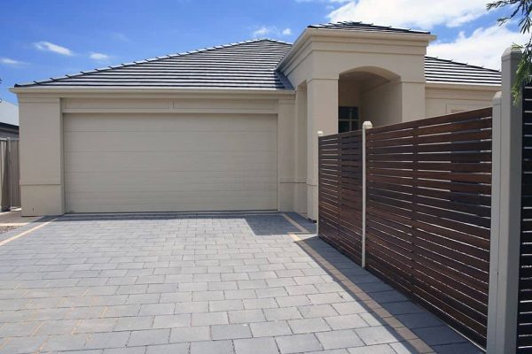 Cement paving stones form a driveway leading up to a blank garage door in this modern Australian house.